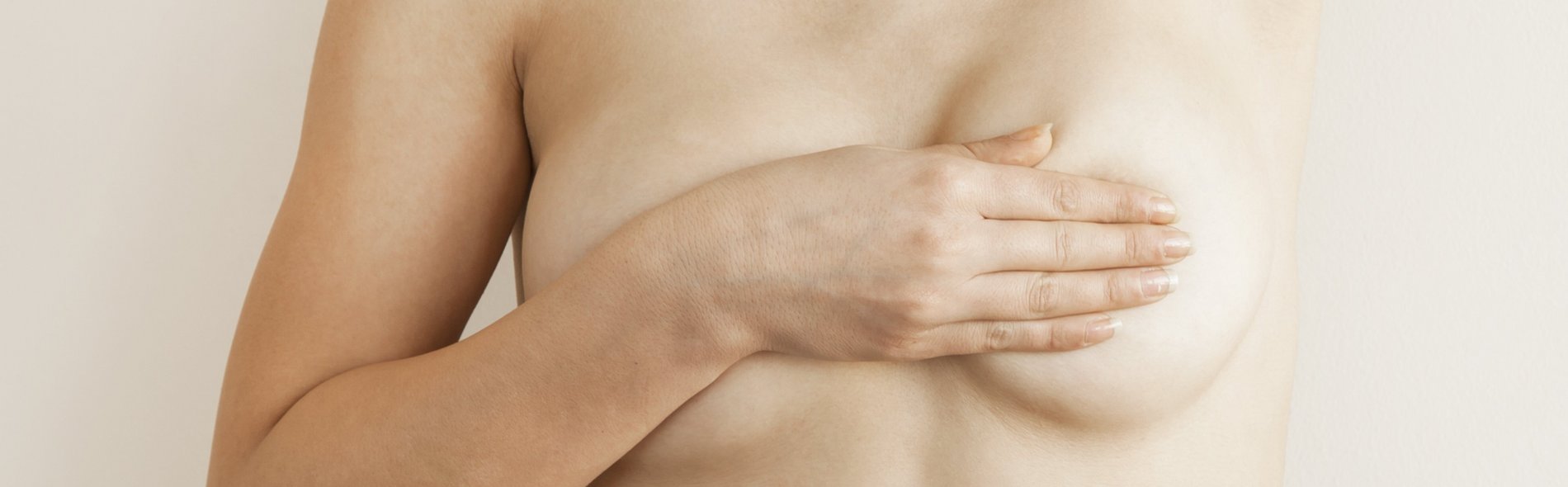 Detailbild des nackten Oberkörpers einer Frau, die ihre linke Brust nach veränderungen, Auffälligkeiten oder Knoten abtastet